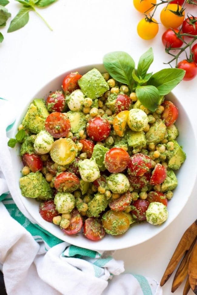 Avocado Chickpea Pesto Salad plated in a bowl with Diced avocados, tomatoes chickpeas & mozzarella balls tossed in a fresh pesto sauce. 