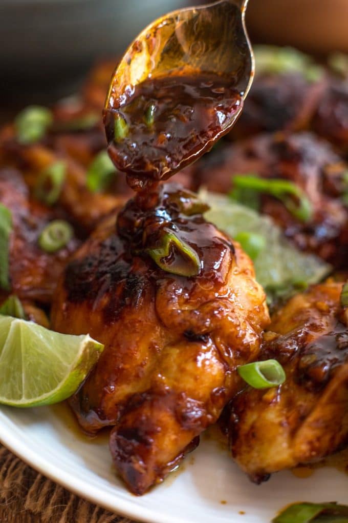 a spoon pouring more sauce over a plate of Honey Sriracha Chicken 