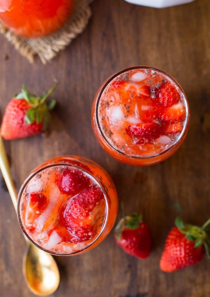 a couple of glasses of strawberry lemonade on a serving board