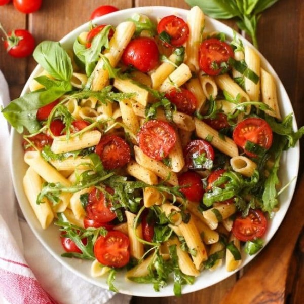 Tomato & Arugula Balsamic Pasta Salad surrounded by fresh ingredients
