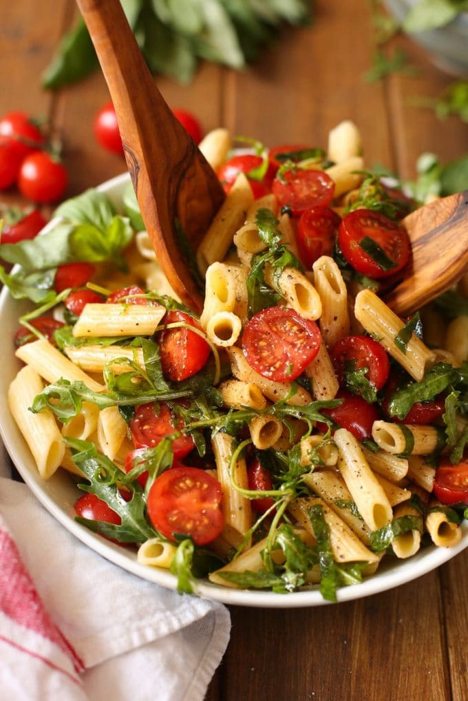 salad tongs tossing together a Tomato & Arugula Balsamic Pasta Salad