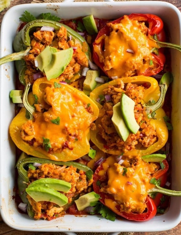 taco stuffed peppers - some topped with cheese and some topped with avocado