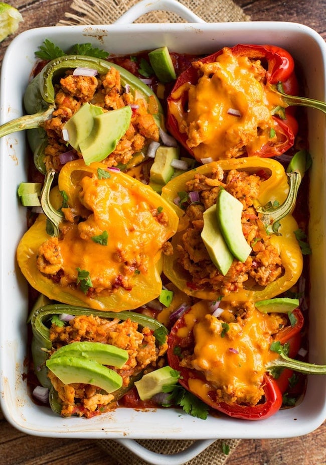 taco stuffed peppers - some topped with cheese and some topped with avocado 