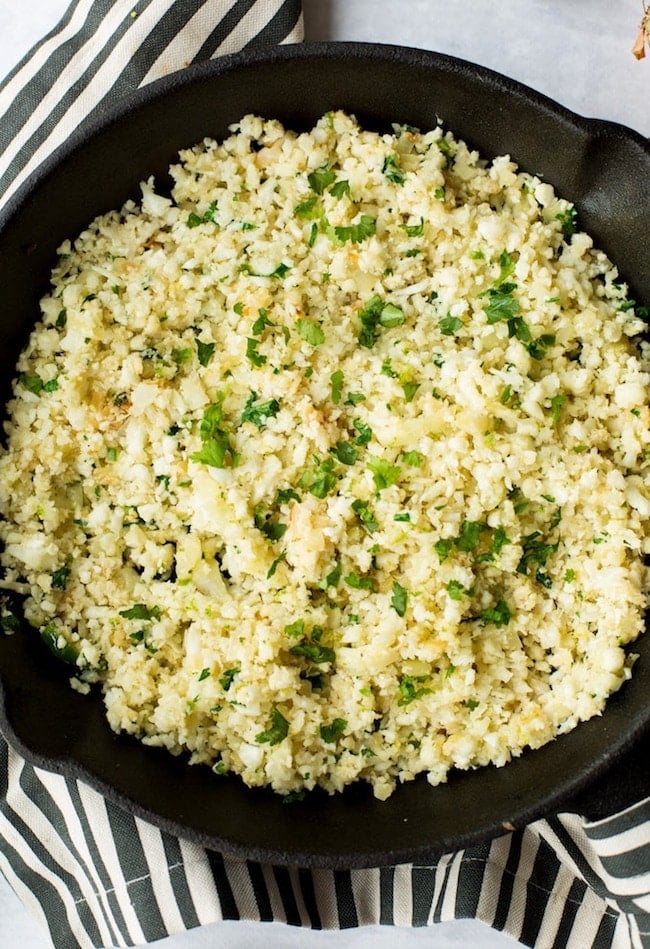 Cilantro Lime Cauliflower Rice in a cast iron skillet topped with chopped cilantro