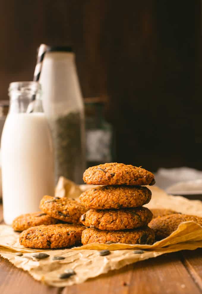 a stack of  Sweet Potato Breakfast Cookies on a piece of baking paper with more cookies piled in the back