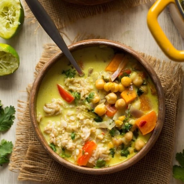 Chickpea Lime & Coconut Soup in a wooden bowl with limes on the side