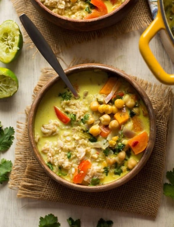 Chickpea Lime & Coconut Soup in a wooden bowl with limes on the side