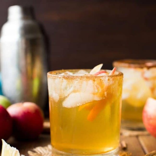 Apple Margarita in a glass with apple slices surrounded by cinnamon sticks