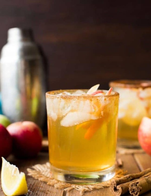 Apple Margarita in a glass with apple slices surrounded by cinnamon sticks