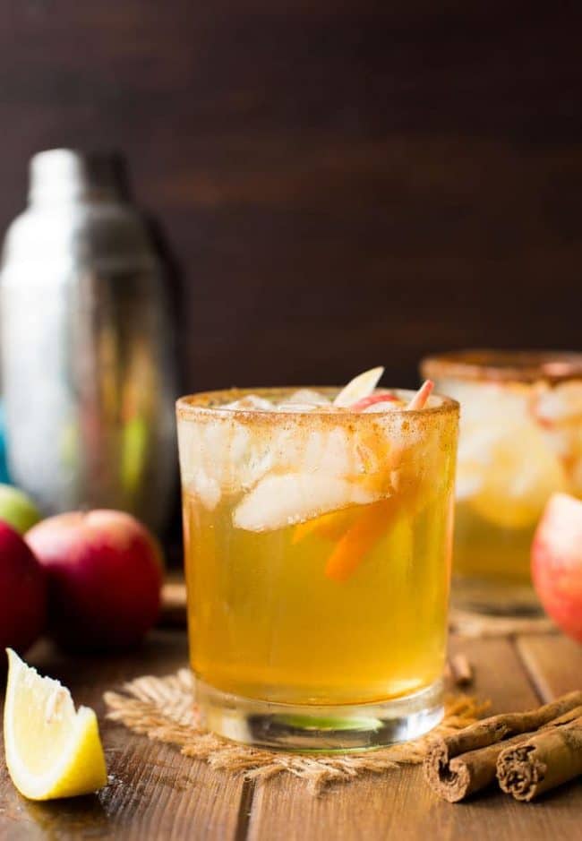 Apple Margarita in a glass with apple slices surrounded by cinnamon sticks