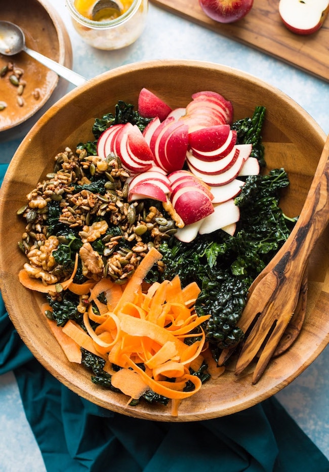 Crunchy kale apple salad in a salad bowl with salad tongs