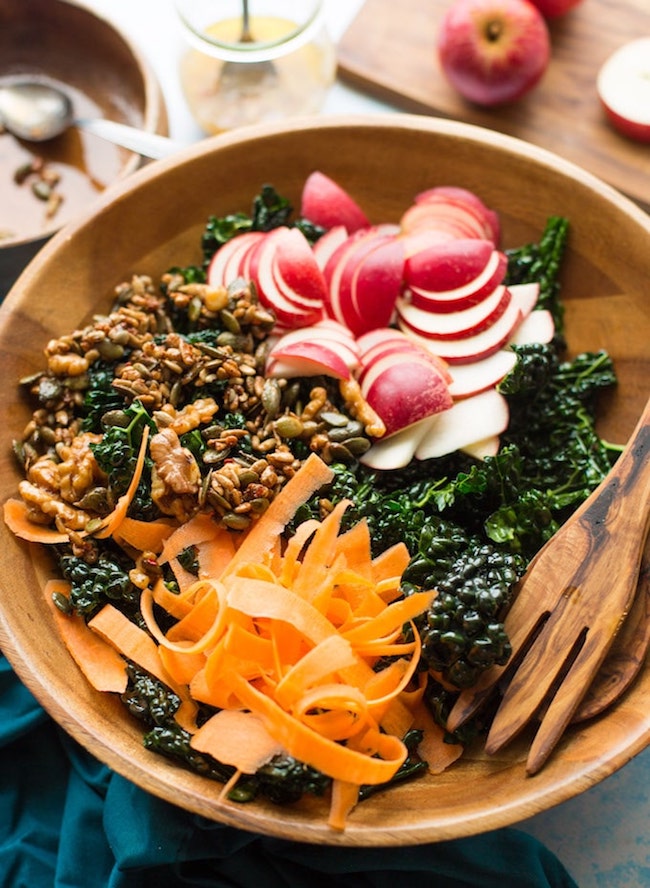 Crunchy kale apple salad in salad bowl: carrot, apple, nut + seed mixture