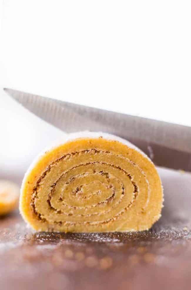  Gain Free Cinnamon Roll Cookies dough rolled up and being cut with a knife