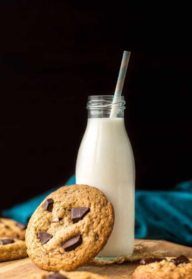 Soft and chewy Paleo Chocolate Chip Cookies - one cookie leaning against a glass of milk