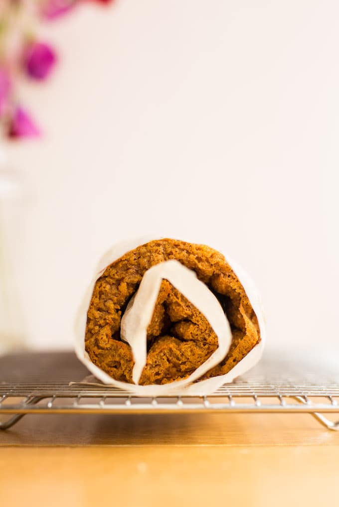 Tender, moist and flavourful Paleo Pumpkin Roll - a light and fluffy almond based cake filled with a simple cashew cream! | Gluten Free + Dairy Free | Cake rolled up in parchment paper before being filled