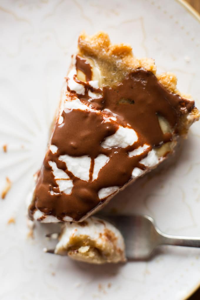 Rich and decedent Vegan Banoffee Pie - a simple, almond flour crust topped with silky caramel, banana, coconut whipped cream and a drizzle of chocolate | Gluten Free + Paleo | Single slice of pie 