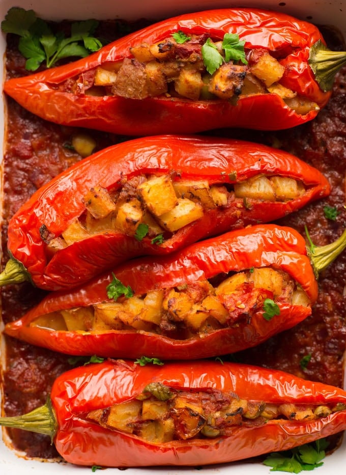 four Potato and Olive Stuffed Banana Peppers over tomato sauce with freshly torn parsley over the top