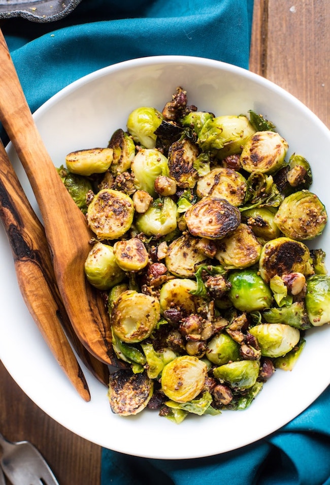 sauteed brussels sprouts with mustard and hazelnuts in a white serving bowl 