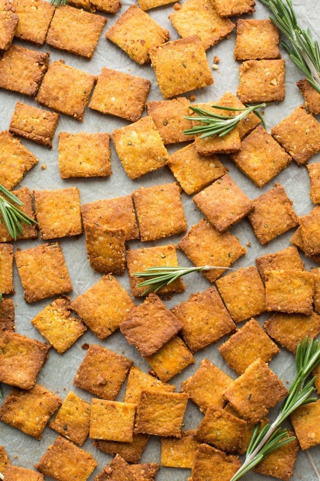 Sweet Potato Paleo Crackers spread out on a baking sheet with rosemary