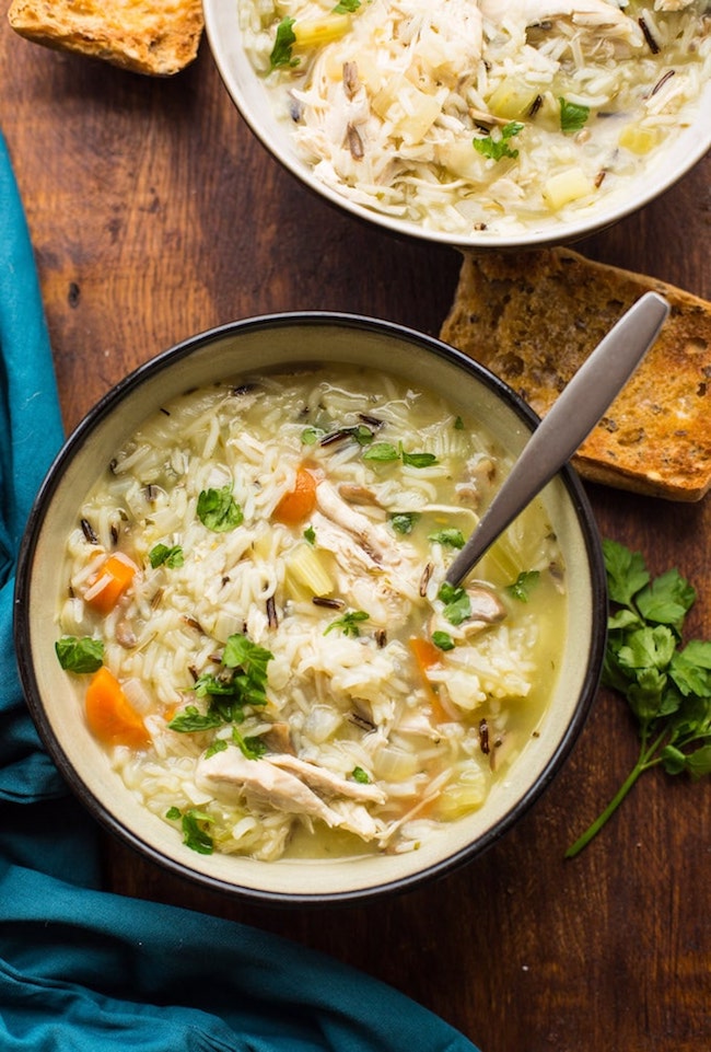 instant pot chicken and wild rice soup in a bowl with a spoon and a piece of bread next to it