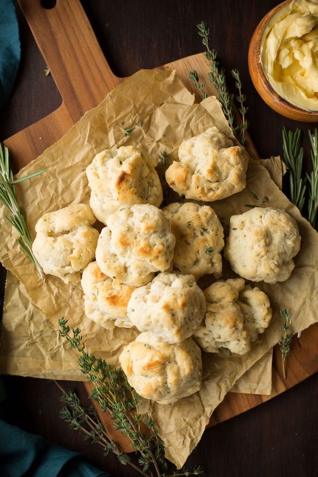 Vegan & gluten free biscuits on a cutting board surrounded by herbs