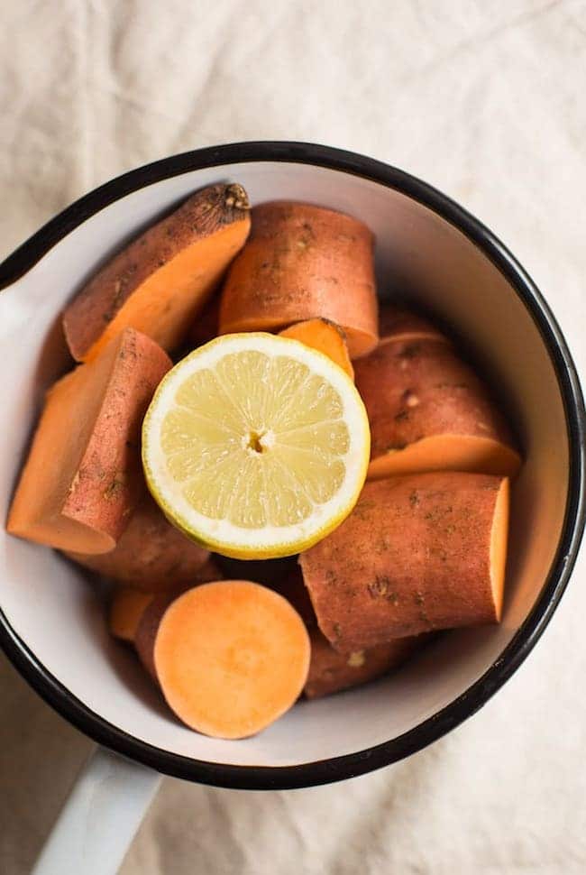 Chopped sweet potato and half lemon in cooking pot