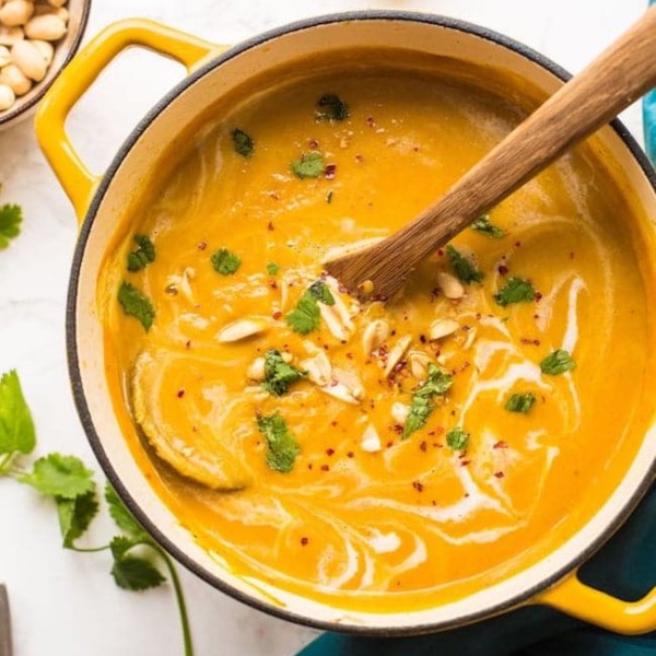 Peanut-Carrot-Sweet-Potato-Soup in a pot with peanuts and a soup ladle