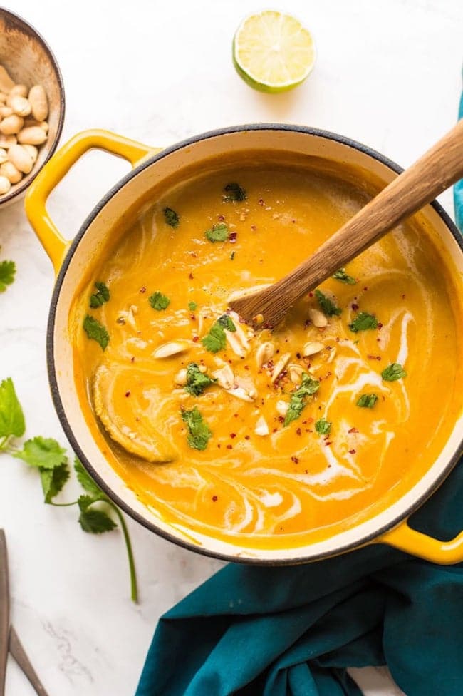Peanut-Carrot-Sweet-Potato-Soup in a pot with peanuts and a soup ladle 
