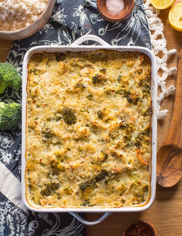 chicken broccoli cauliflower casserole on a wooden table with broccoli and spoon next to it