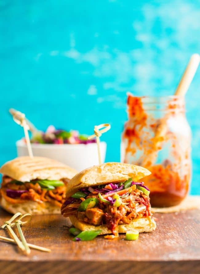 BBQ Jackfruit Pulled 'Pork' Sandwich on a cutting board with BBQ sauce in the background