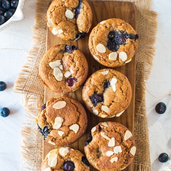 Paleo Vegan Blueberry Muffins on a wooden board topped with flaked almonds