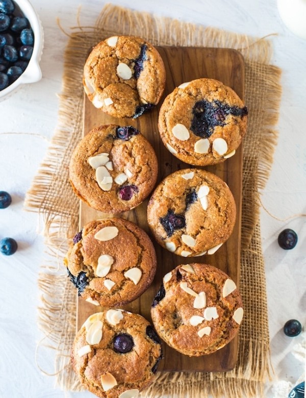 Paleo Vegan Blueberry Muffins on a wooden board topped with flaked almonds