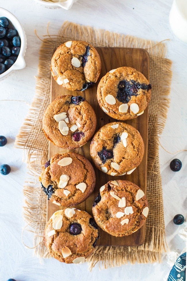 Paleo Vegan Blueberry Muffins on a wooden board topped with flaked almonds