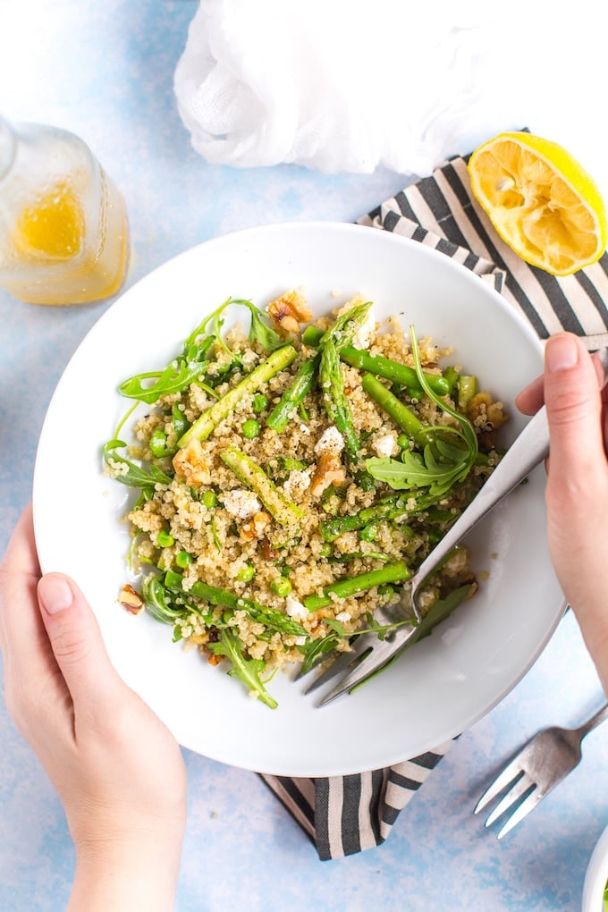 Spring Quinoa Pea & Asparagus Salad in a serving bowl held up by hands