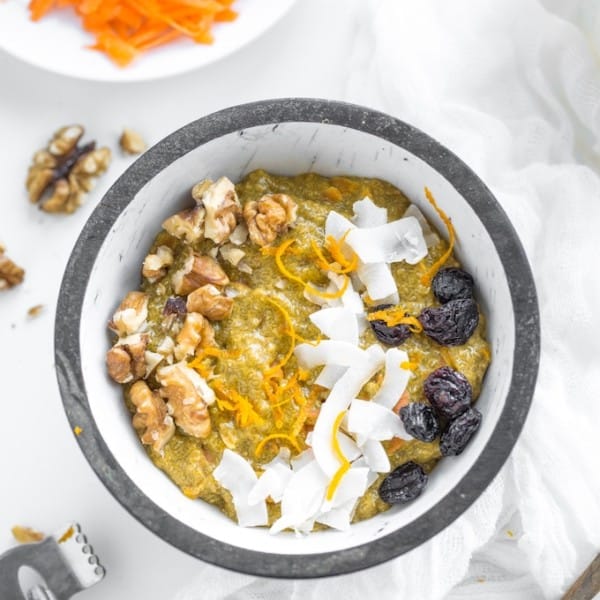 Turmeric-Carrot-Chia-Pudding-in a bowl topped with fresh carrot, coconut and raisins