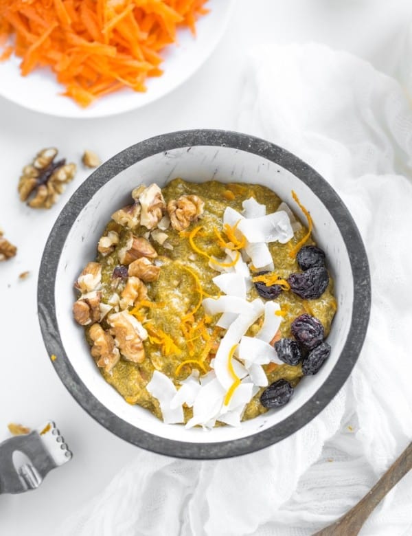 Turmeric-Carrot-Chia-Pudding-in a bowl topped with fresh carrot, coconut and raisins