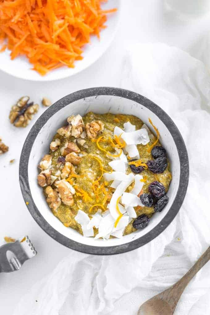 Turmeric-Carrot-Chia-Pudding-in a bowl topped with fresh carrot, coconut and raisins