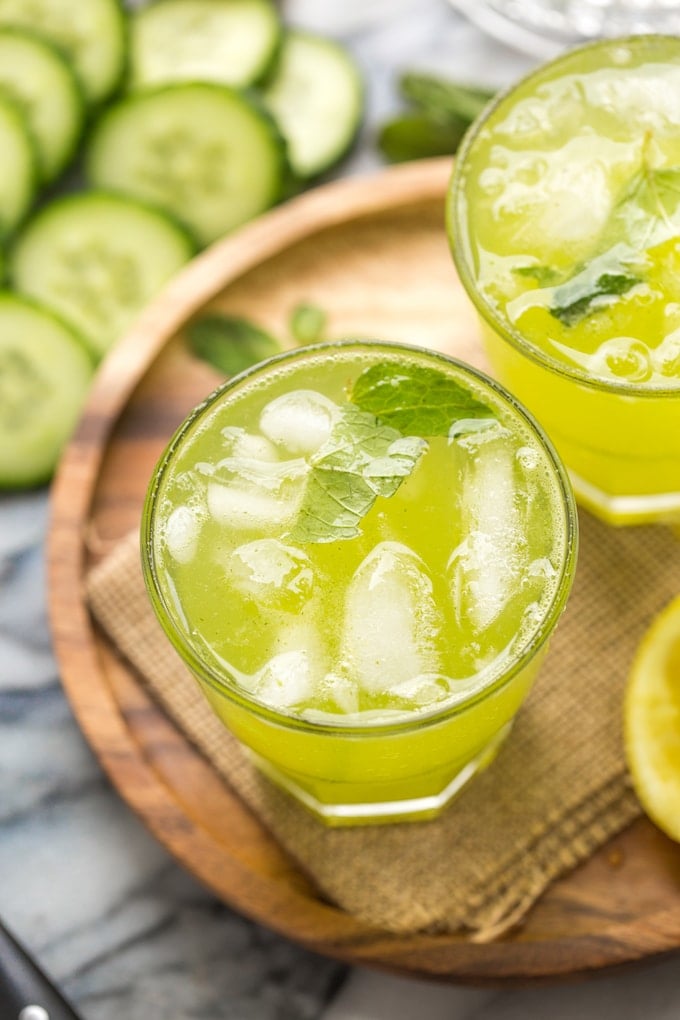 Minty Cucumber Lemonade with ice surrounded by cucumbers