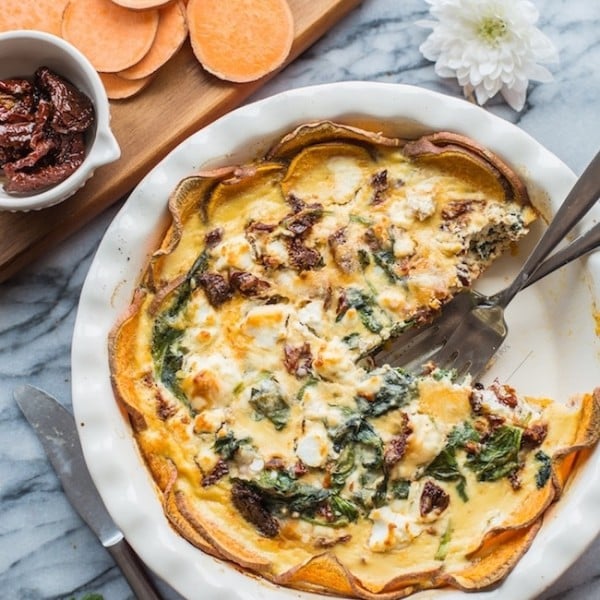 sun dried tomato quiche in a pie pan with a piece missing