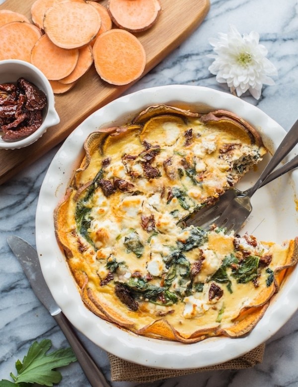 sun dried tomato quiche in a pie pan with a piece missing