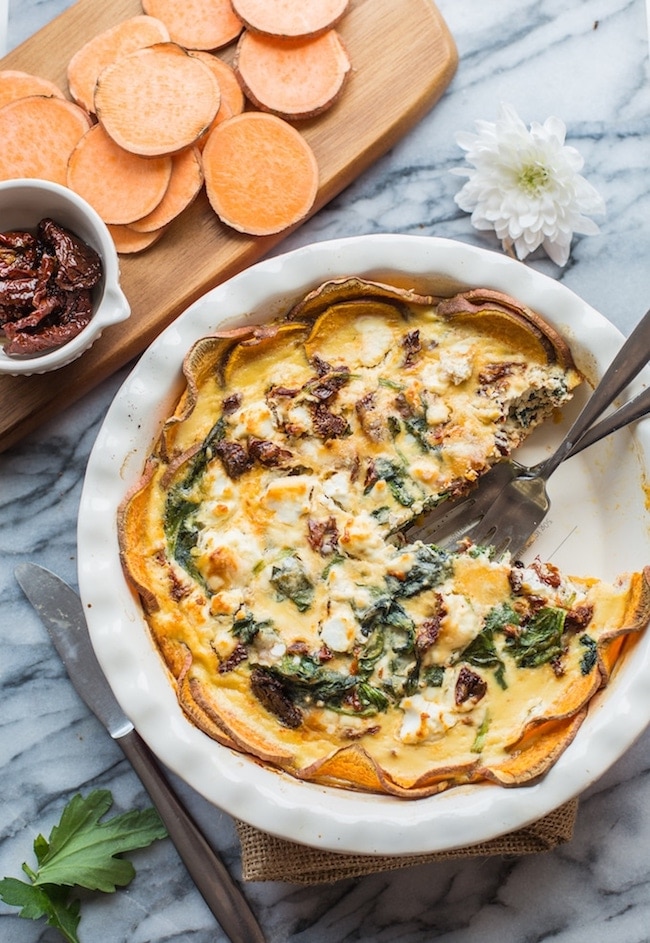 sun dried tomato quiche in a pie pan with a piece missing  