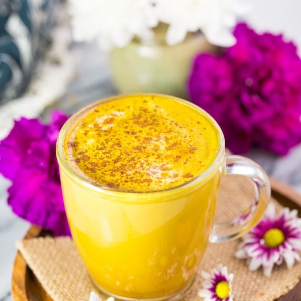 Turmeric Latte on a plate surrounded by flowers