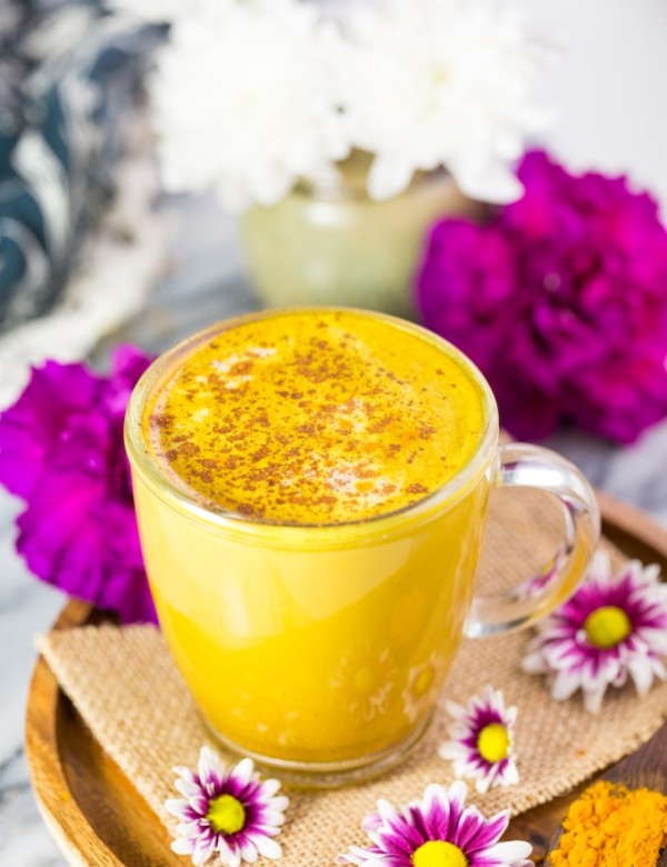 Turmeric Latte on a plate surrounded by flowers