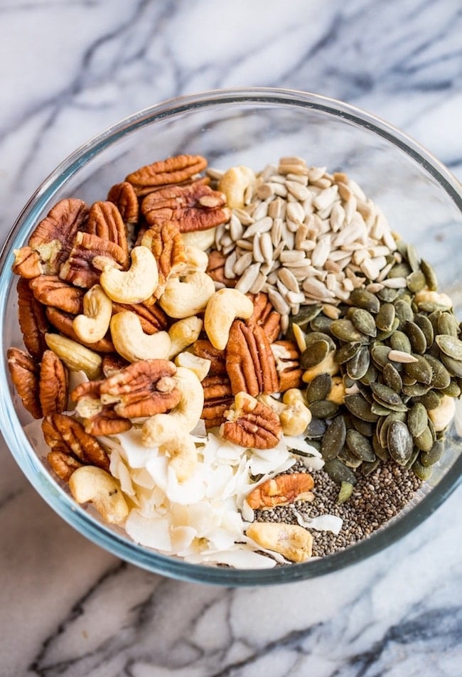 Turmeric Stove Top Paleo Granola ingredients in a mixing bowl: coconut chips, sunflower seeds, pumpkin seeds, pecans, and cashews