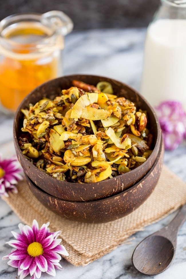 Turmeric & cinnamon spied stove top paleo granola in a cereal bowl surrounded by flowers