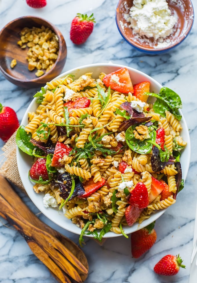 Balsamic Strawberry Pasta Salad in a bowl surrounded by strawberries and feta