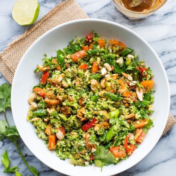 Chopped Thai Broccoli Salad in a bowl with lime on the side, springs of cilantro and cashews