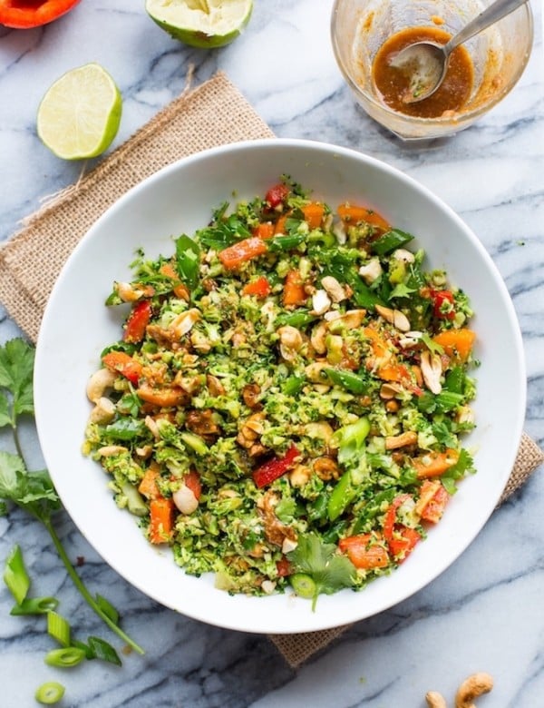 Chopped Thai Broccoli Salad in a bowl with lime on the side, springs of cilantro and cashews