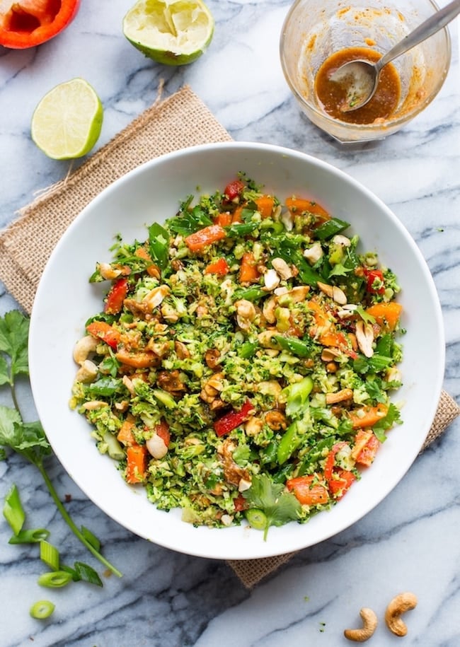 Chopped Thai Broccoli Salad in a bowl with lime on the side, springs of cilantro and cashews