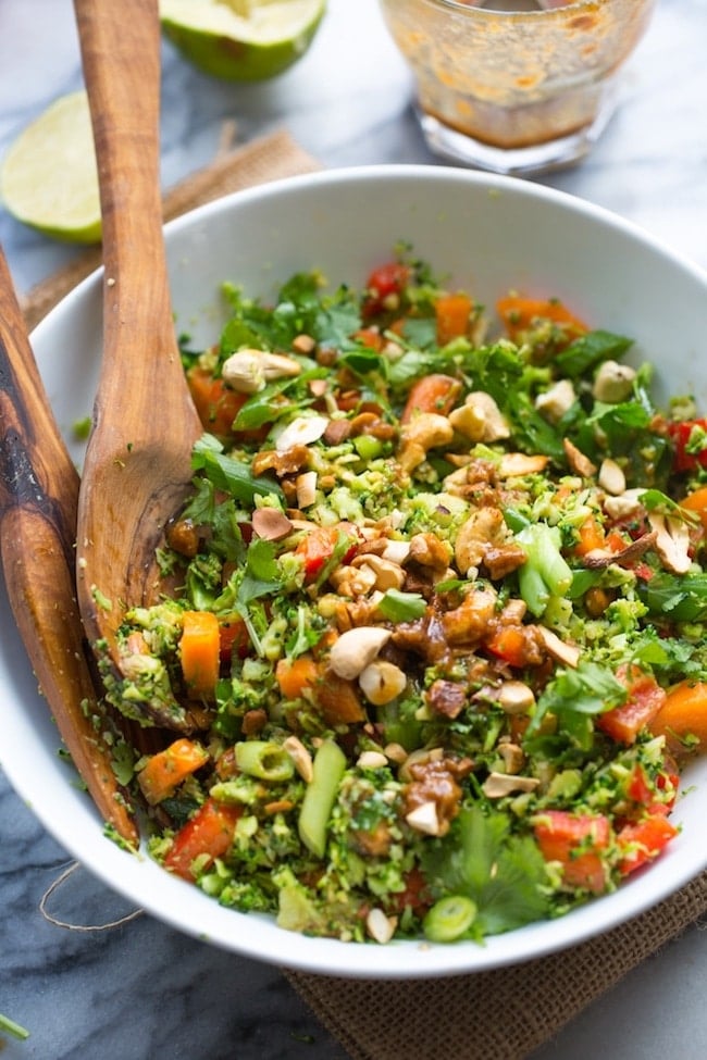 Chopped Thai Broccoli Salad in a bowl with lime on the side, springs of cilantro and cashews